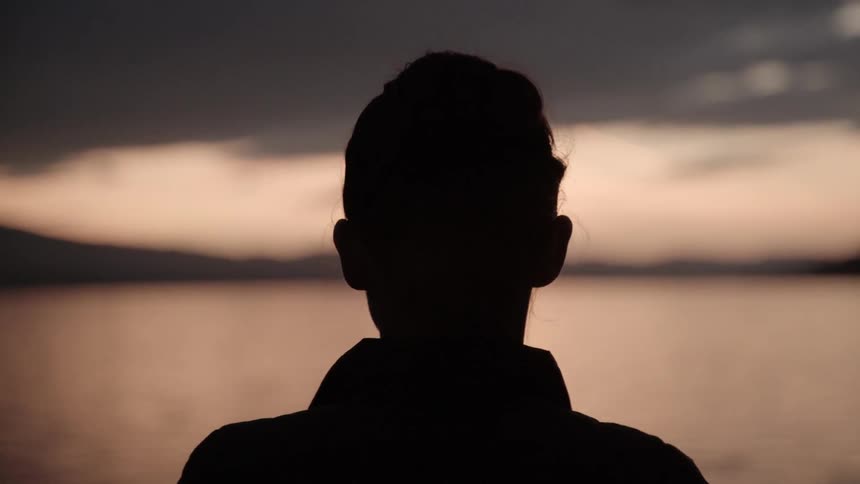 Woman looks at a lake at sunset