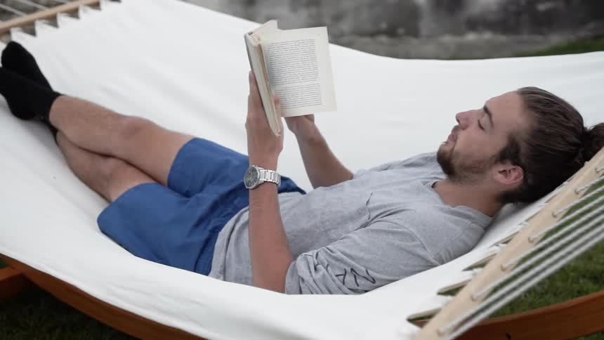 Man reads a book in a hammock