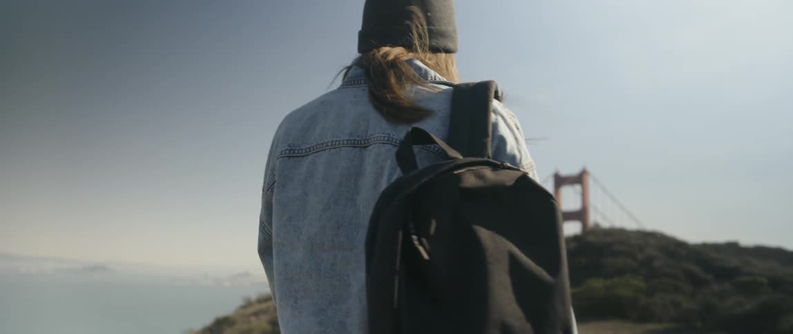 A woman walks towards the golden gate bridge