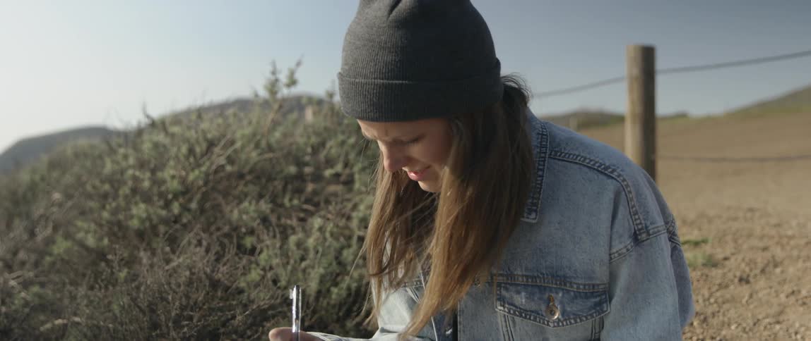 A woman writes in a journal while sitting outside