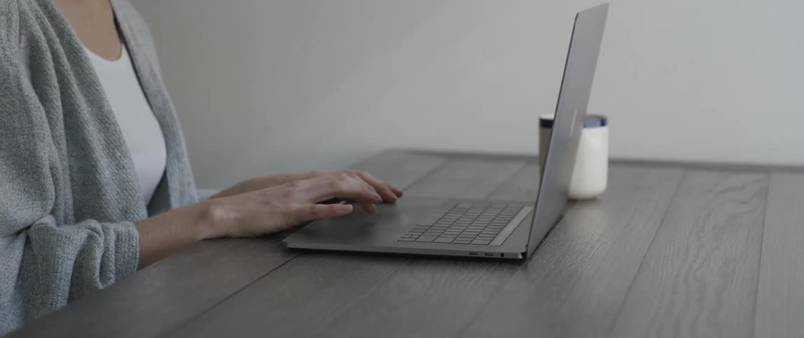 A woman sits at a table and works on a laptop