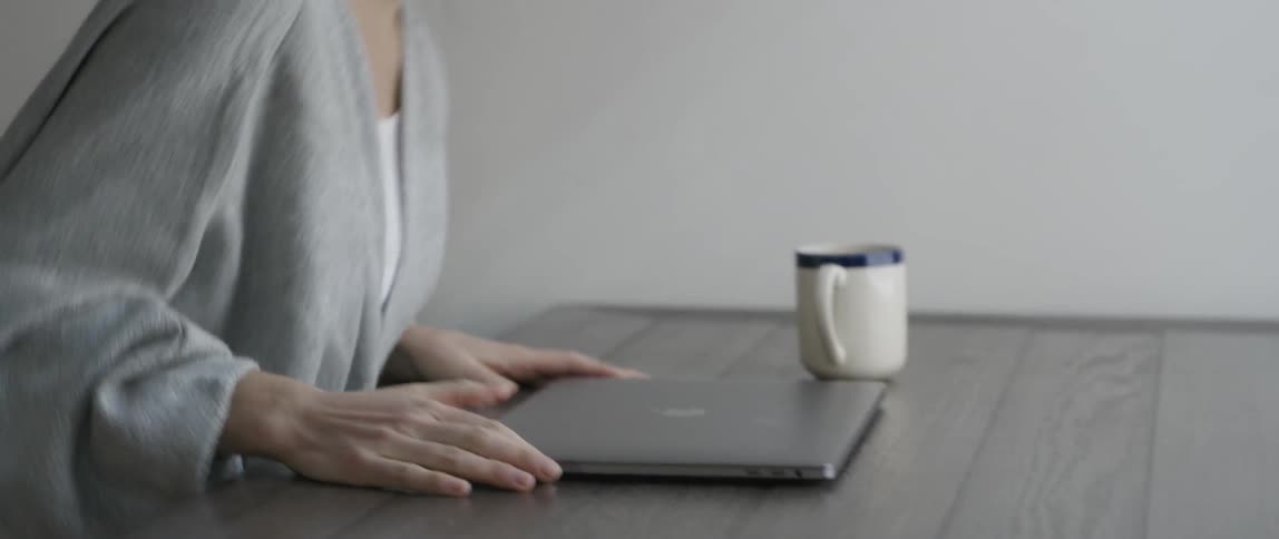 A woman sits down and opens a laptop