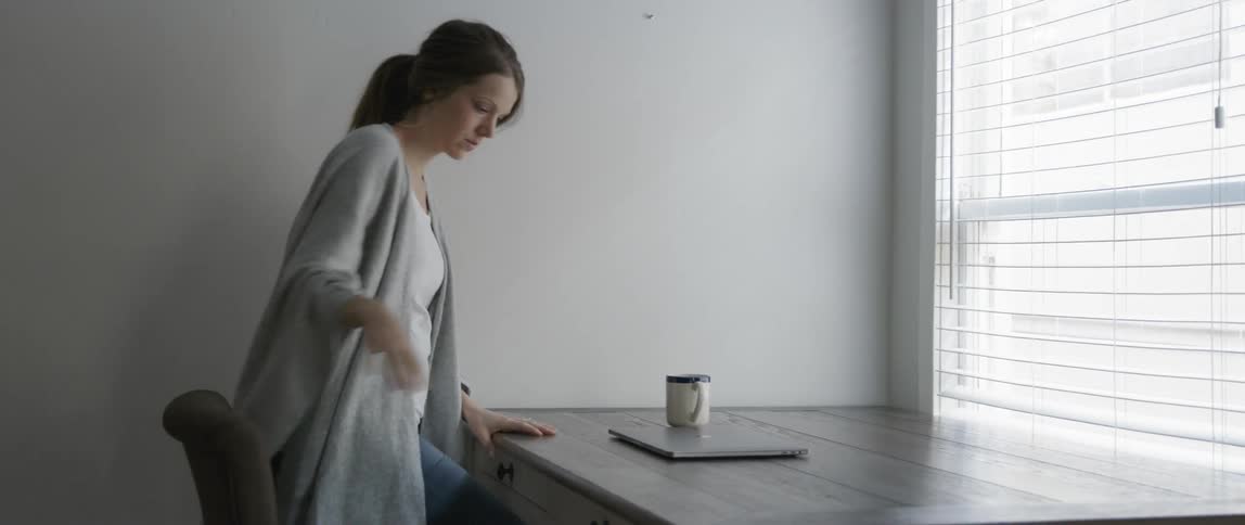 Woman sits at a desk and opens a laptop