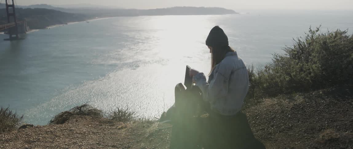 A woman removes her notebook on the hill