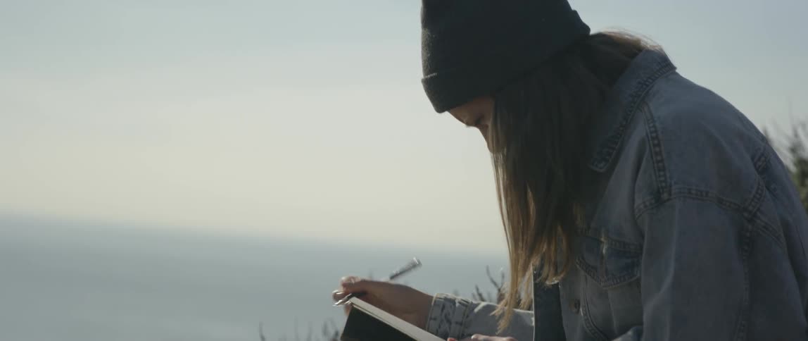 Woman writes in a notebook outside