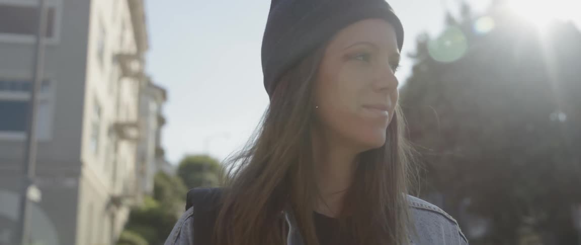 A woman looks around town at the corner and smiles