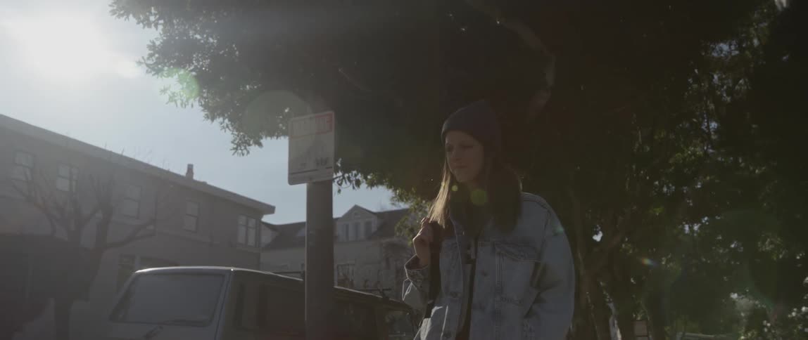 A woman walking down the sidewalk pauses to look at a building