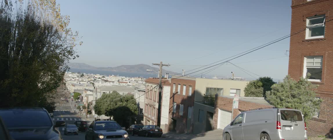 Cars drive on a street up a hill in a large city
