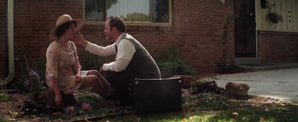 A man and woman sitting and talking outside on the ground