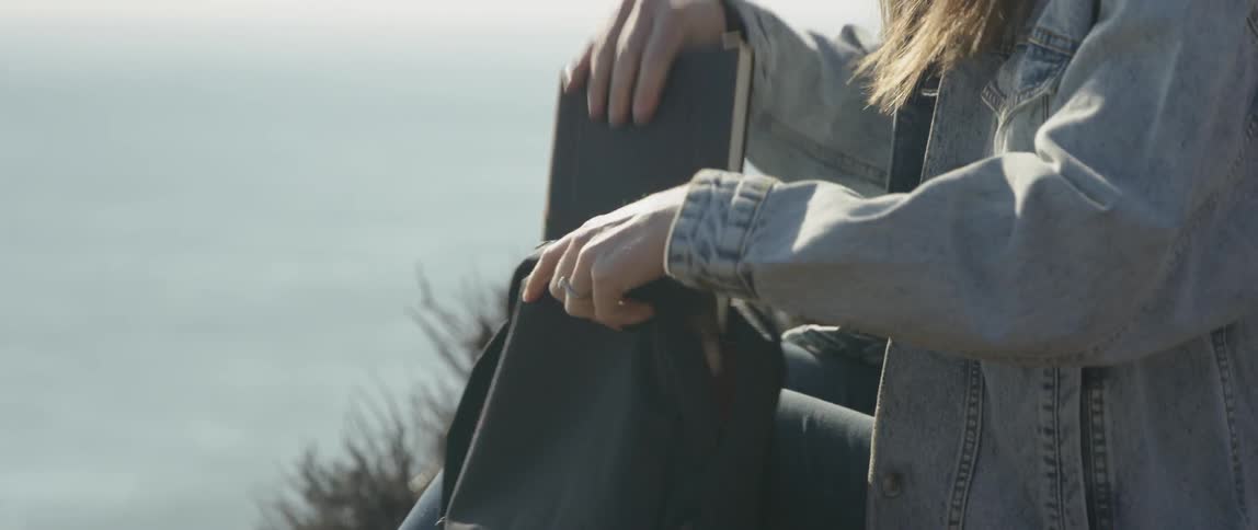 Woman removes a book from a backpack