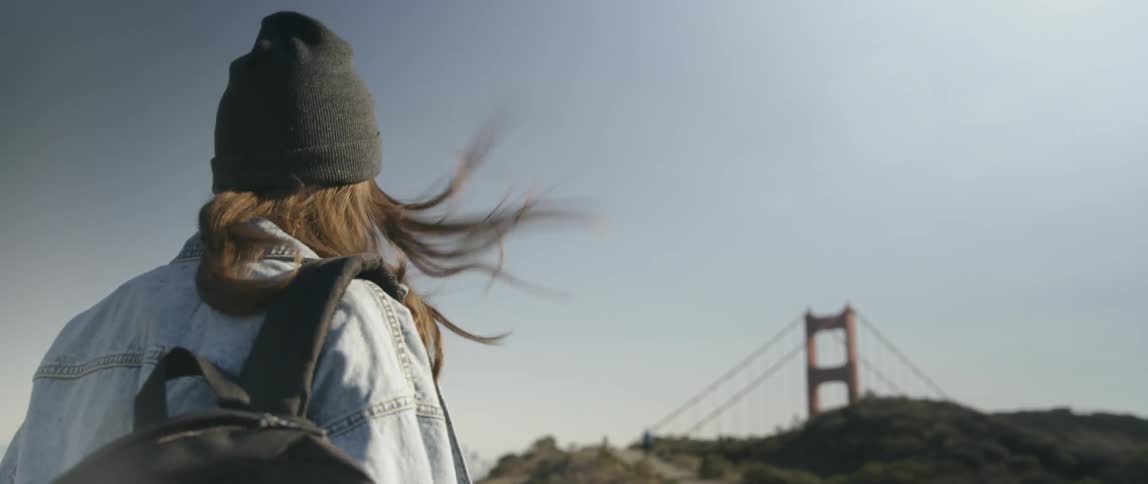 A woman walks towards the golden gate bridge