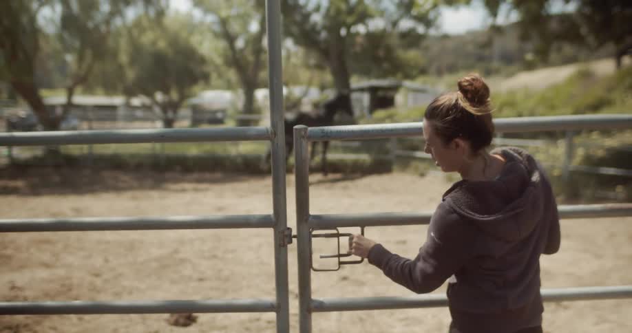 Woman secures a gate on a farm