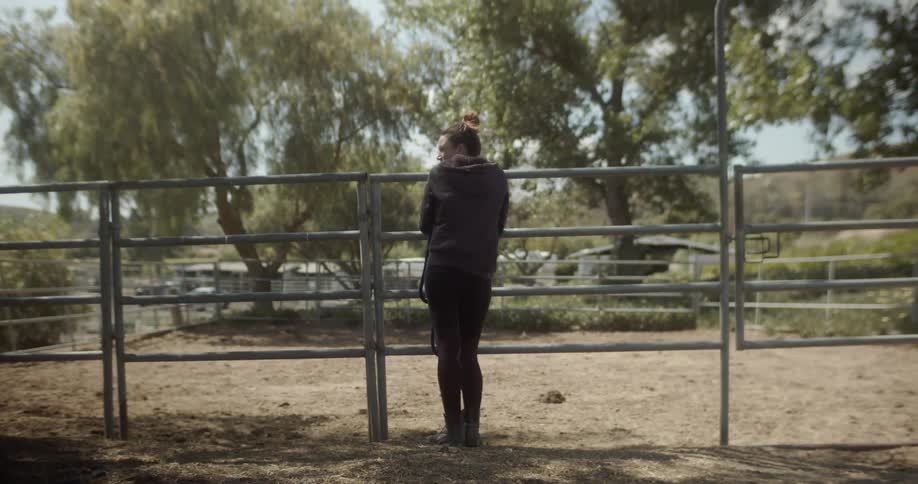 Woman stands next to a paddock on a ranch