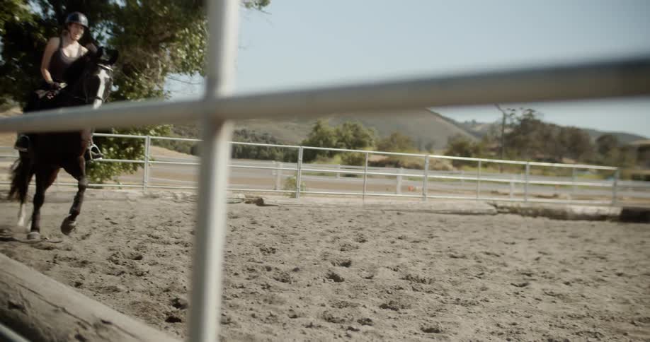 A woman is riding the horse behind the fence