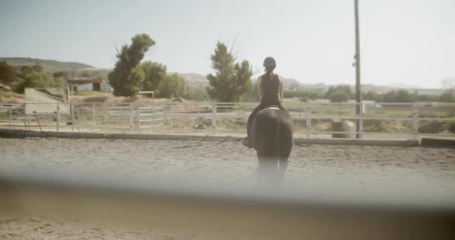 A woman rides a walking horse in a paddock