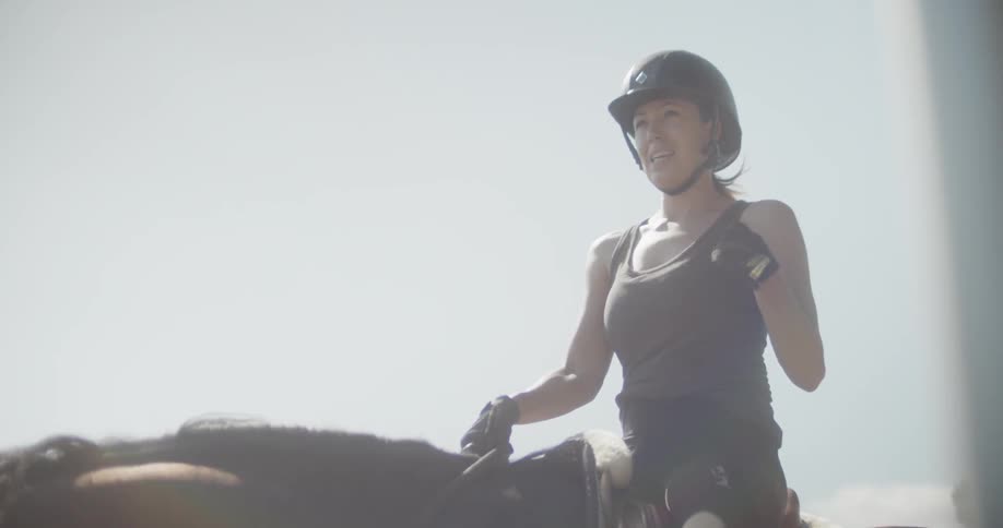 A woman talks as she rides a horse
