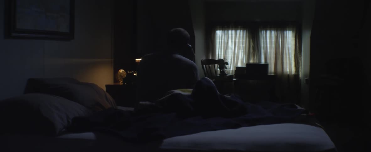 A man answers the telephone in bed
