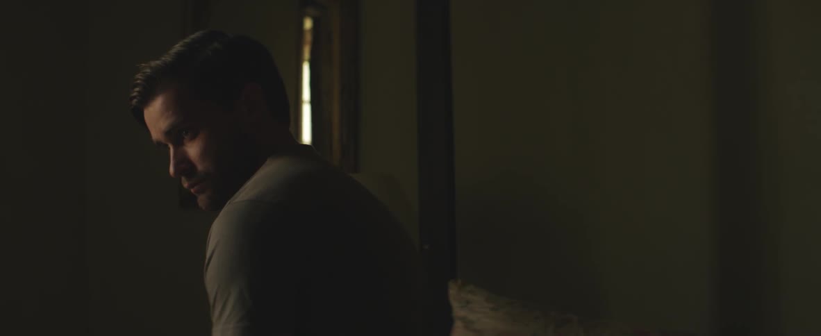 Man sitting in a dark room puts his fist to his chin
