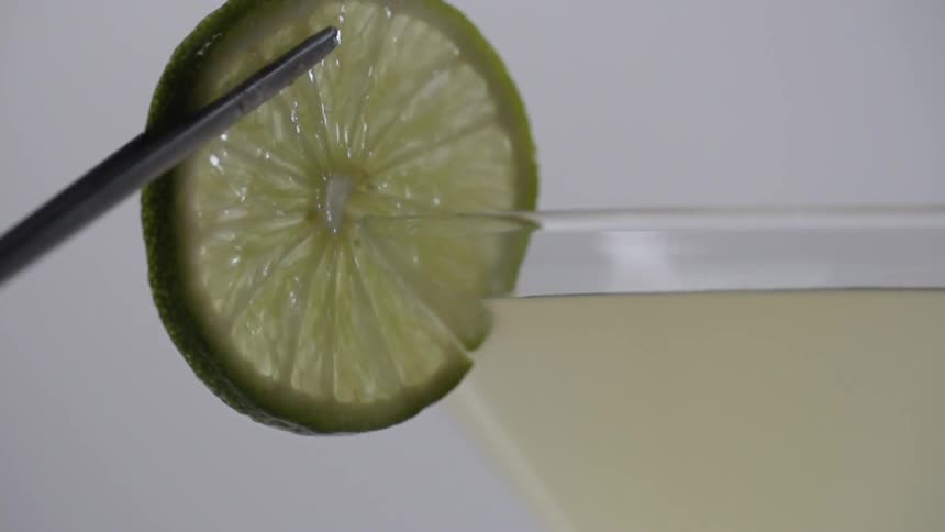 A lime slice is placed on a cocktail glass