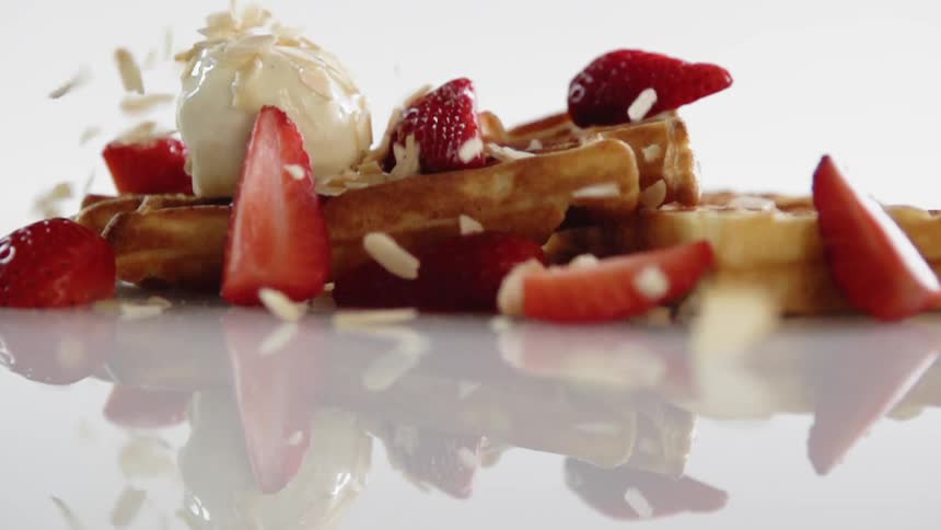 Nuts are sprinkled on some waffles and fruit