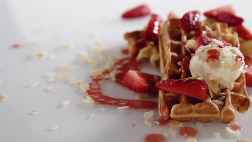 Syrup is poured onto a waffle dessert