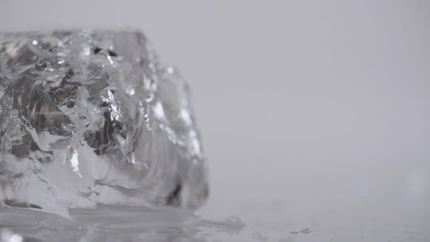 A person uses a fork to cut an ice cube