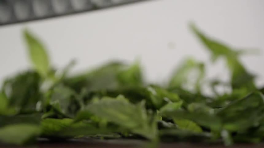 A person is chopping up greens on the board