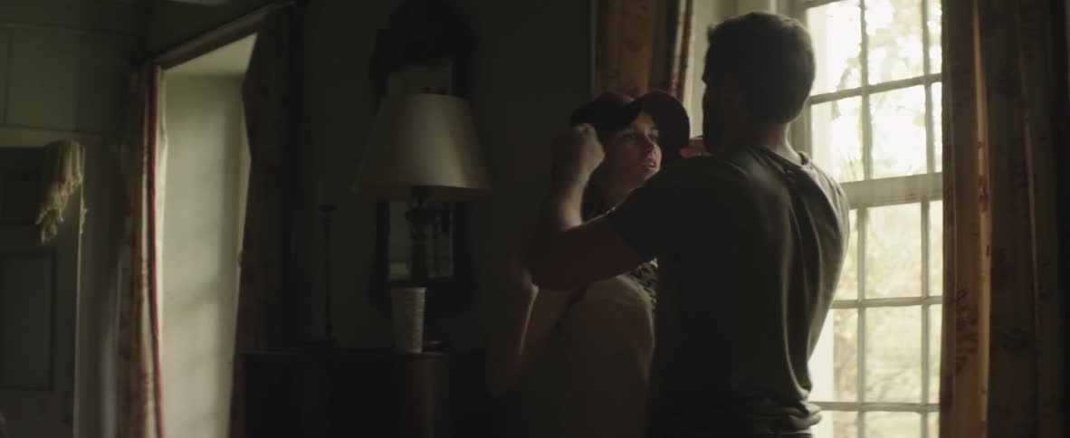 A man and woman hug by a window