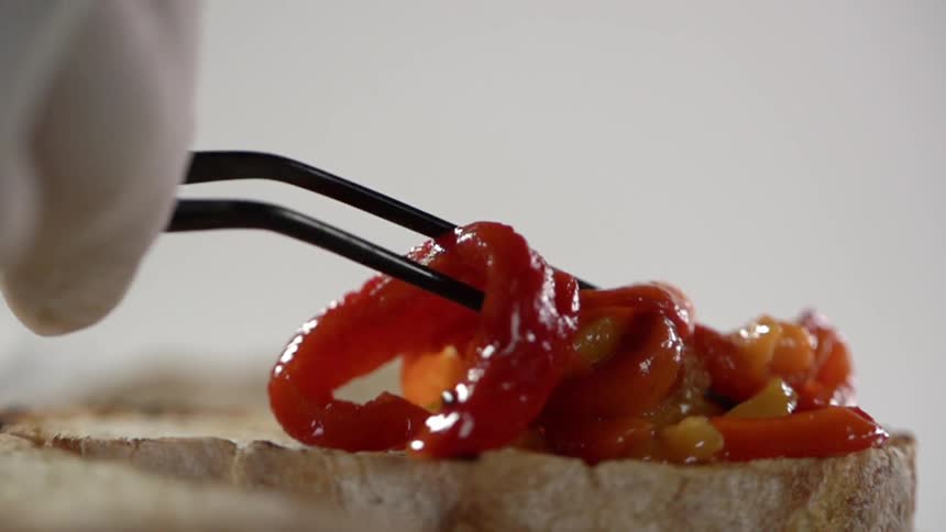 A person places some peppers on the bread
