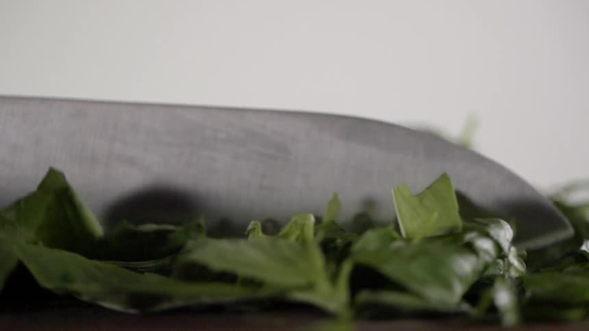A person is cutting some greens on the table