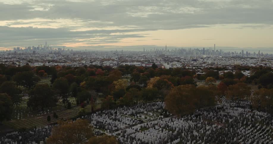 A cemetery sits near city buildings at sunset