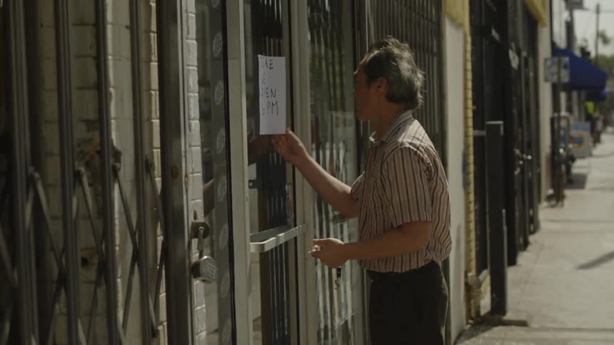 Man unlocks the door to a business then removes a sign from the door and enters