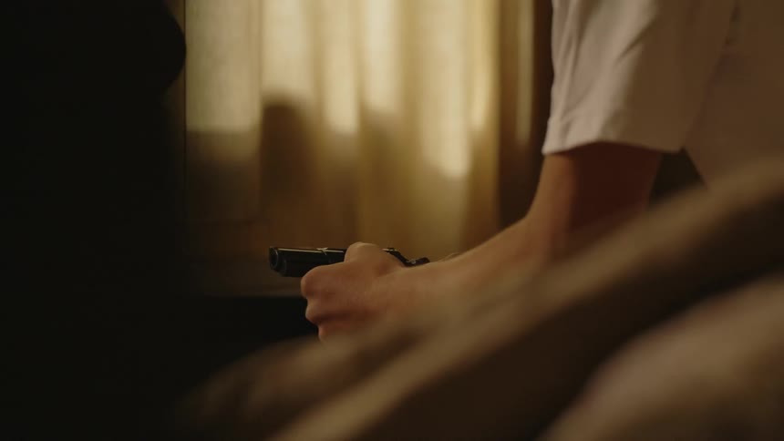 kid holds a handgun at home