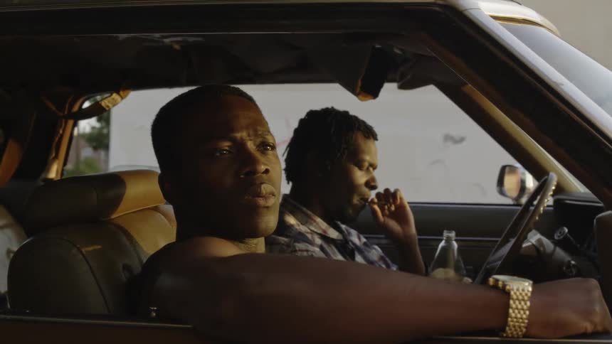 Two men are sitting in the car together smoking