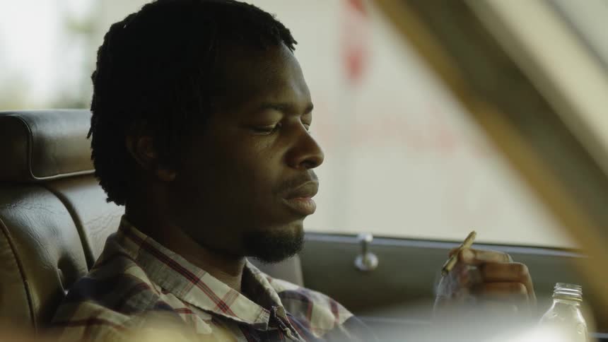 A man smokes in the driver seat of the car