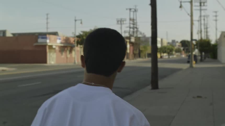 A man is walking down the sidewalk on a sunny day