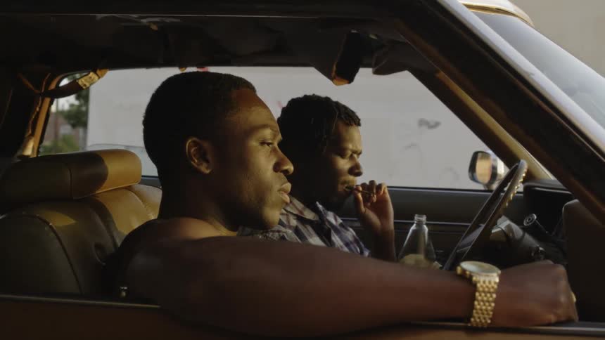 Two men smoke in a parked car