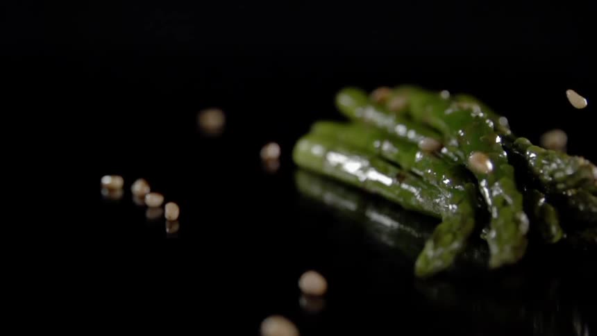 Pine nuts are sprinkled over cooked asparagus