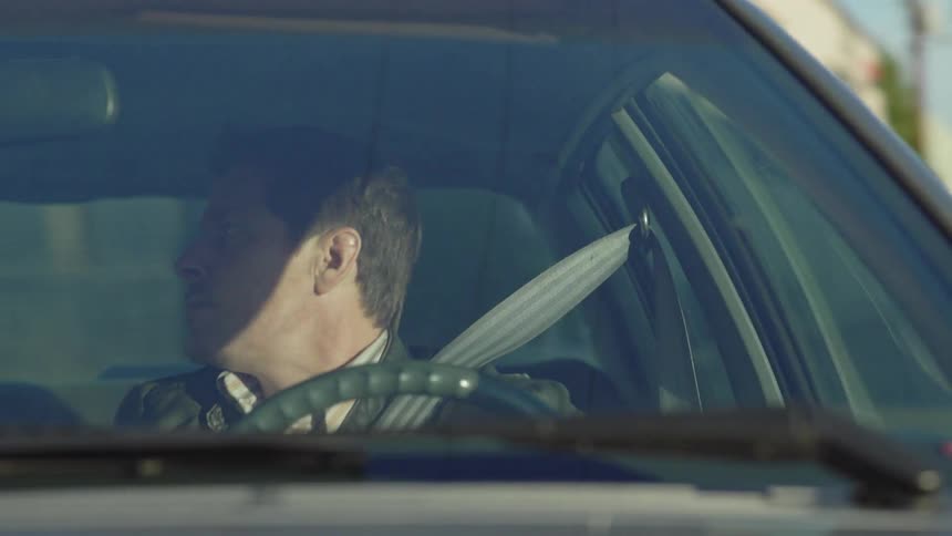 The man is steering the car in town