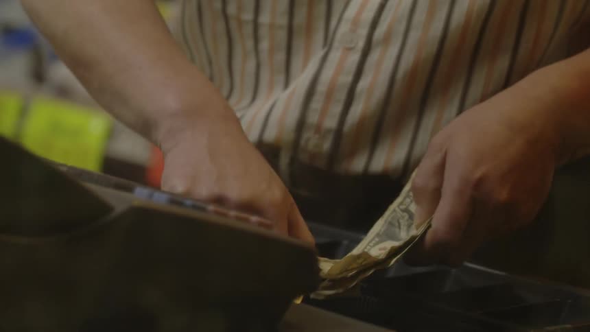 A man counts money near the store register