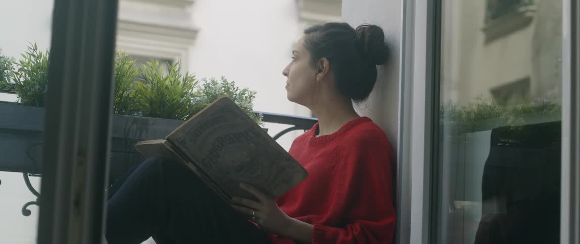 Woman reads on an apartment balcony