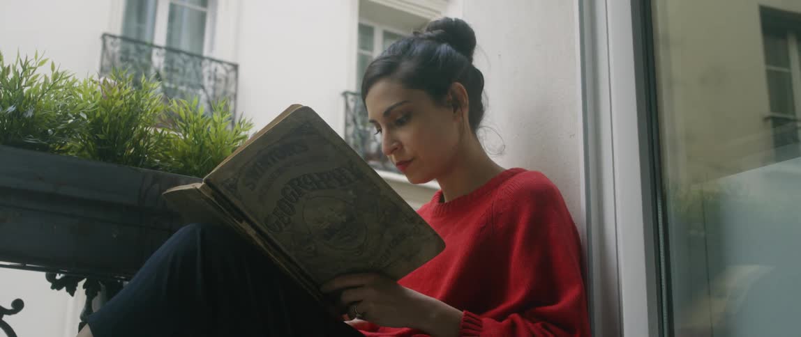 Woman reads a book while sitting on a balcony