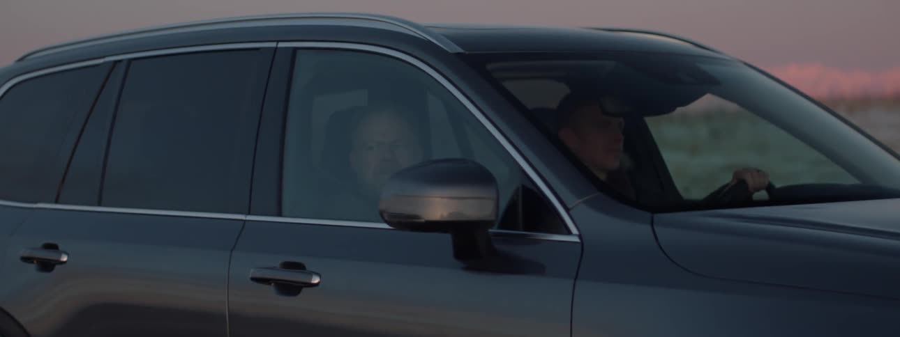 Two men ride in a car at sunset