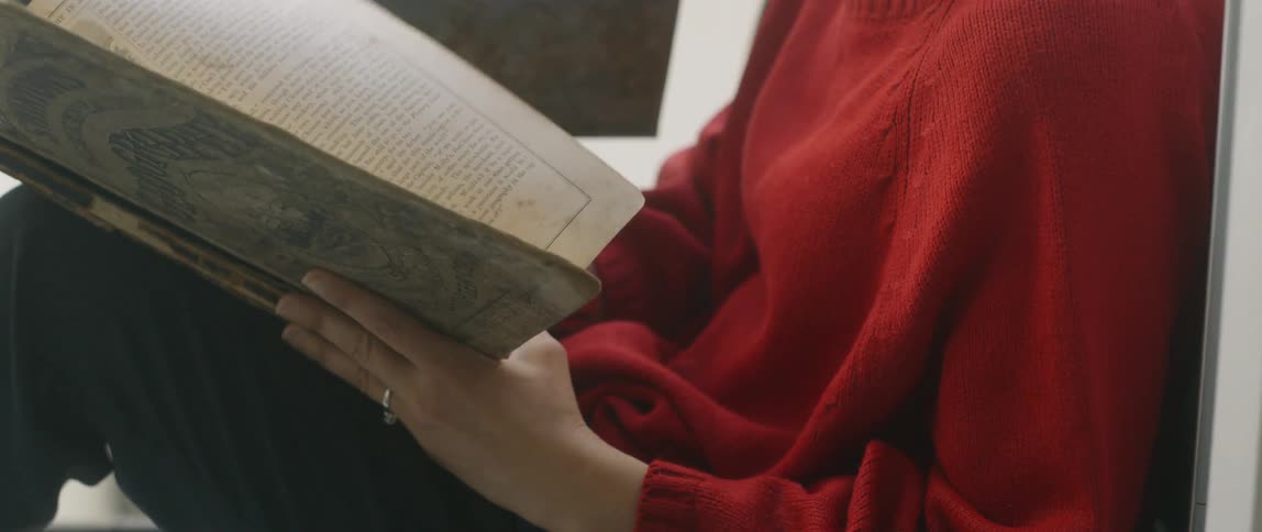 A woman reads her book by the window