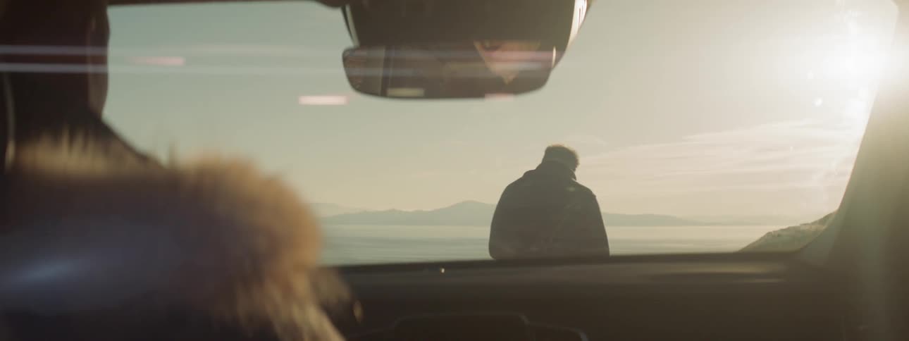 Man walks in front of a parked car at sunset