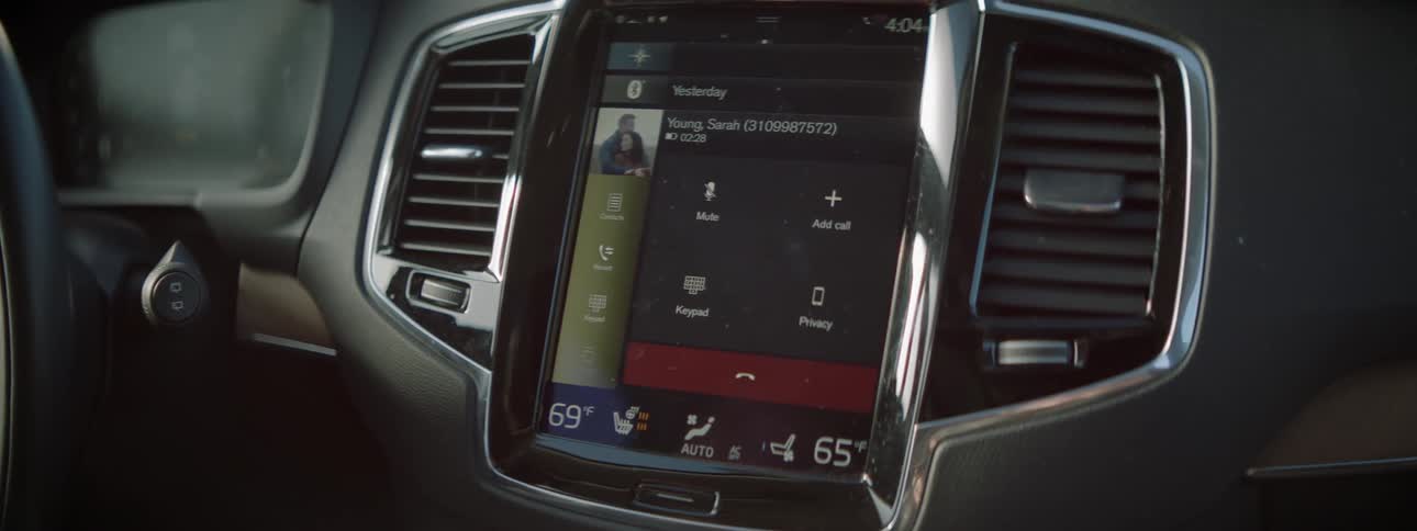 A car dashboard screen displays name and photo of person on the phone