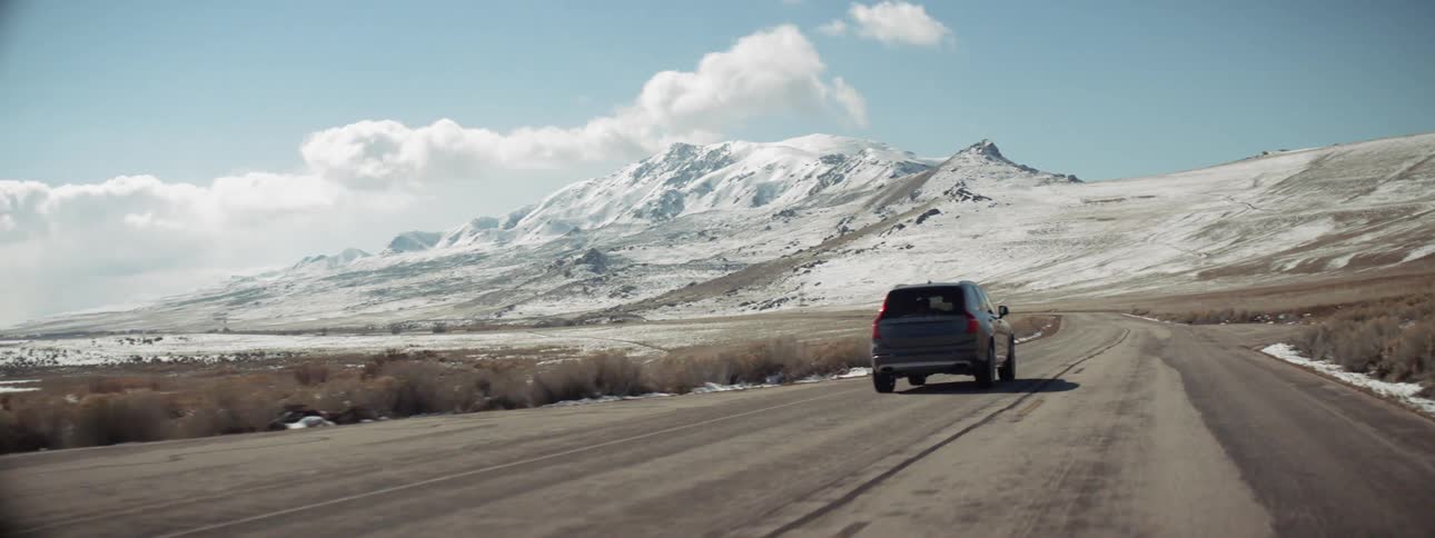 The car races ahead on the road towards the snow covered mountain