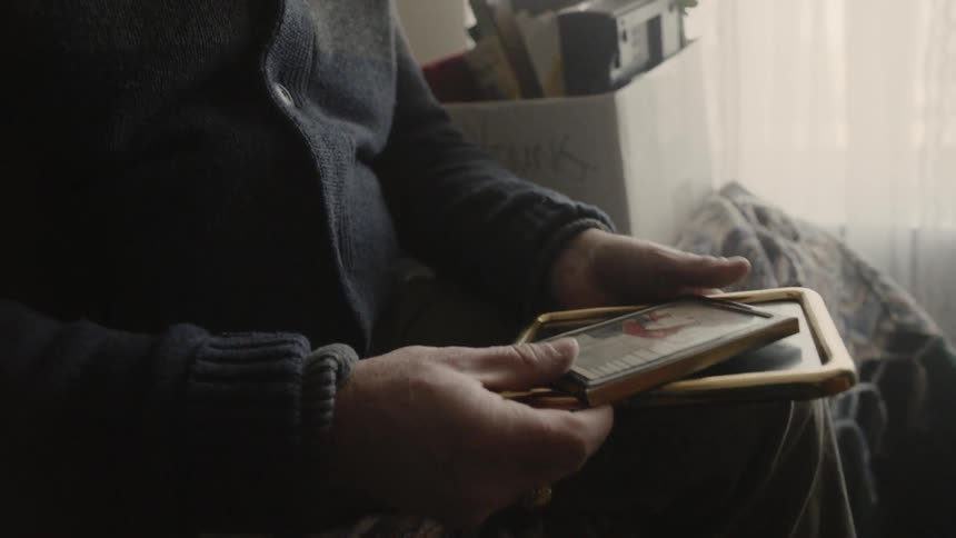 Elderly man takes pictures out of a box and looks at them