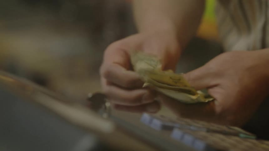 A man takes bills out of a register and counts