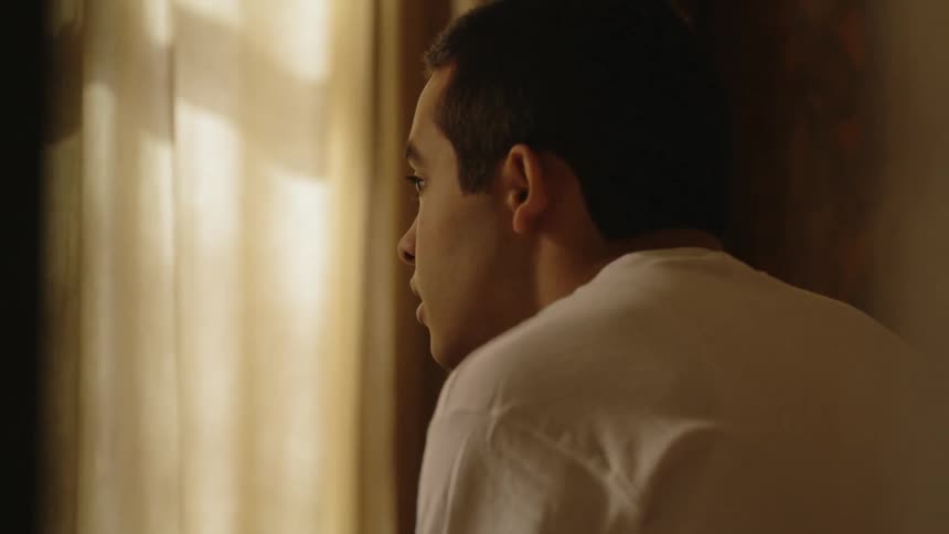 A man leans peeking out the window